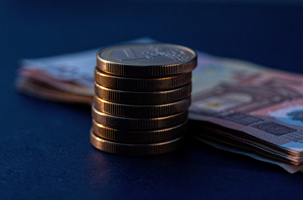 Des pièces et des billets en euros posés sur une surface bleue