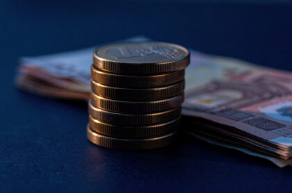 Des pièces et des billets en euros posés sur une surface bleue