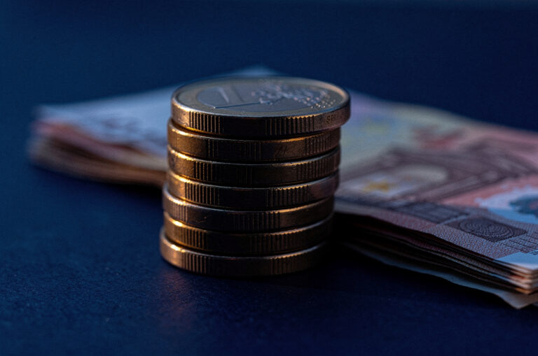 Des pièces et des billets en euros posés sur une surface bleue